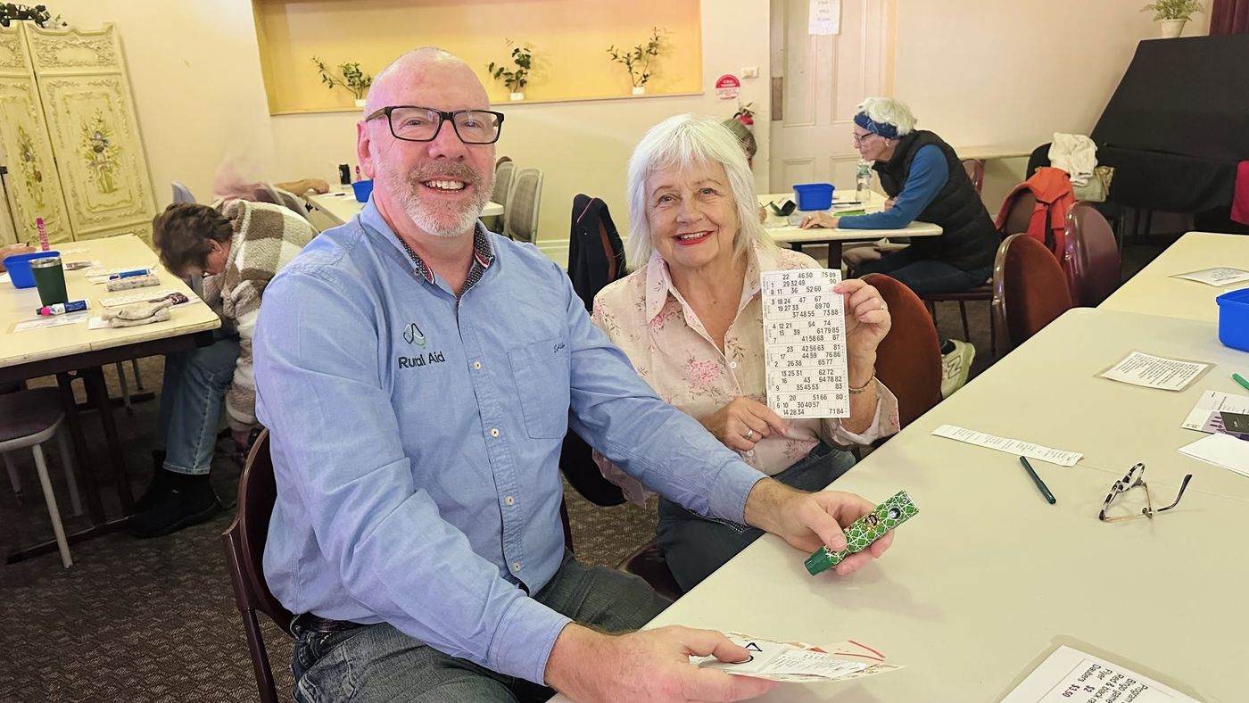 Two smiling players holding a bingo card and dabber