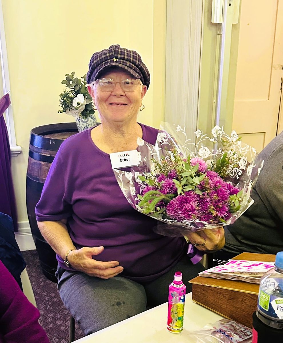 A smiling woman holding a bouquet of purple flowers