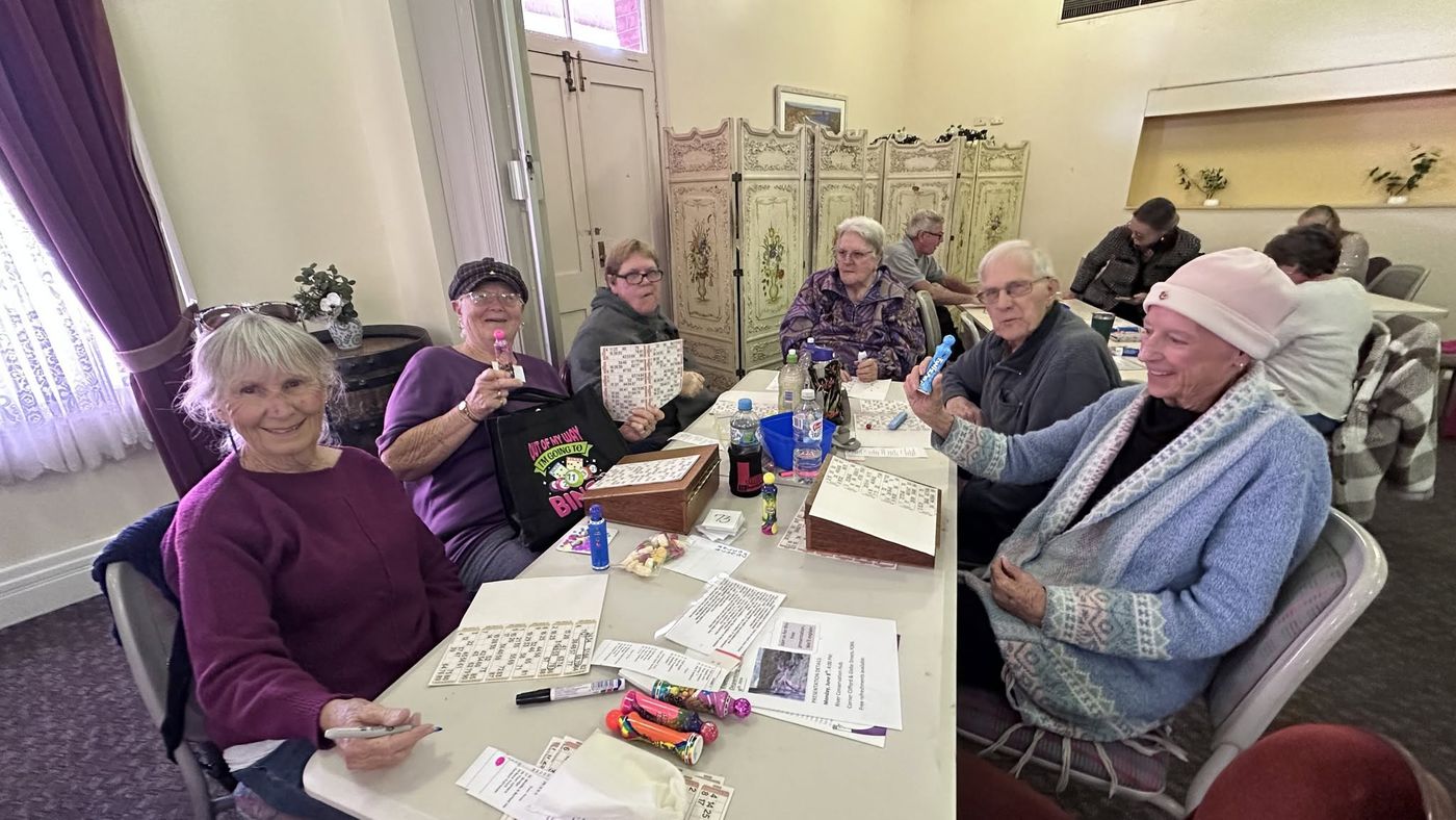 Friends at a table holding bingo dabbers and cards