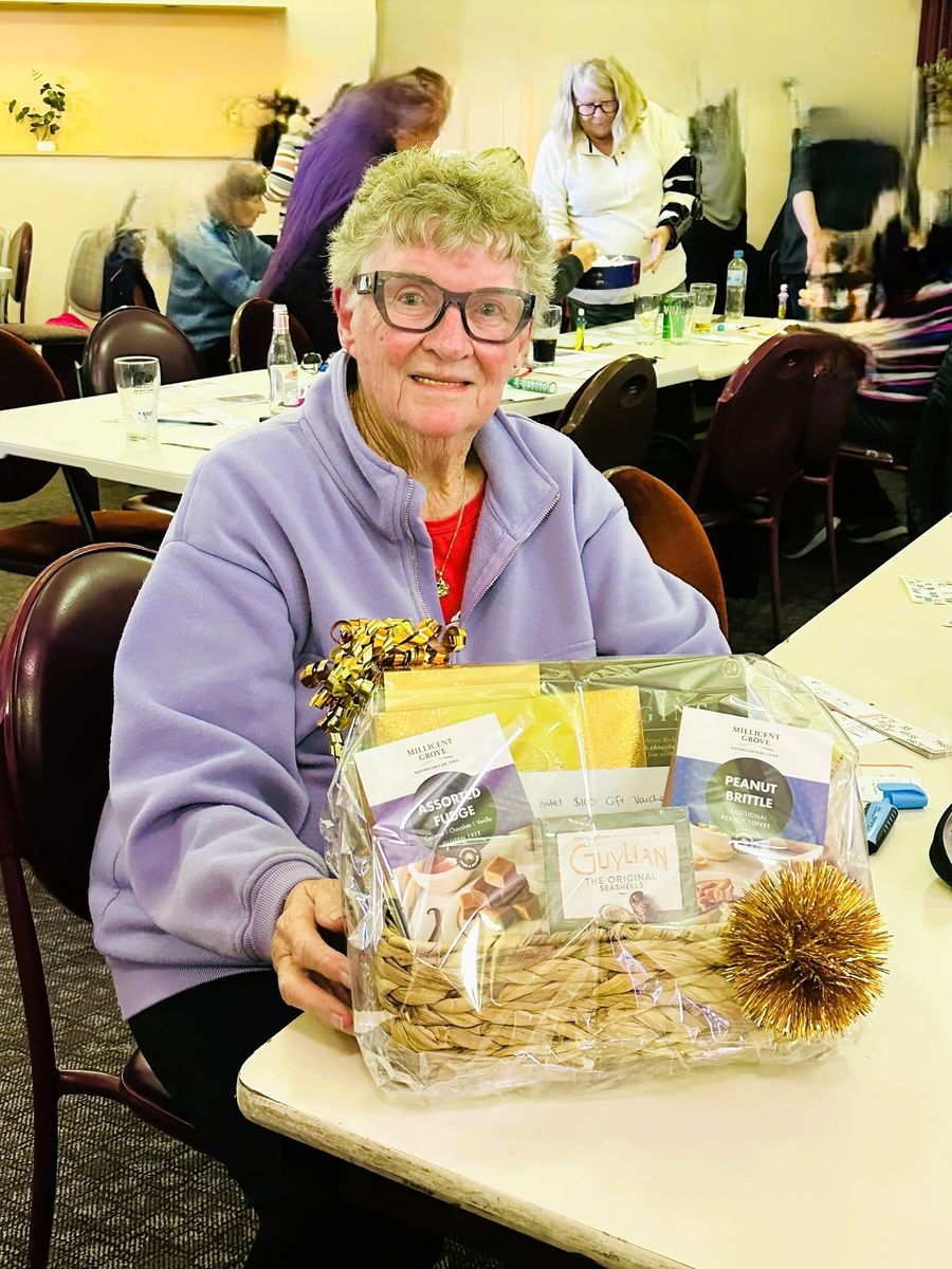 A smiling woman with a gift hamper of fudge, toffee and chocolates