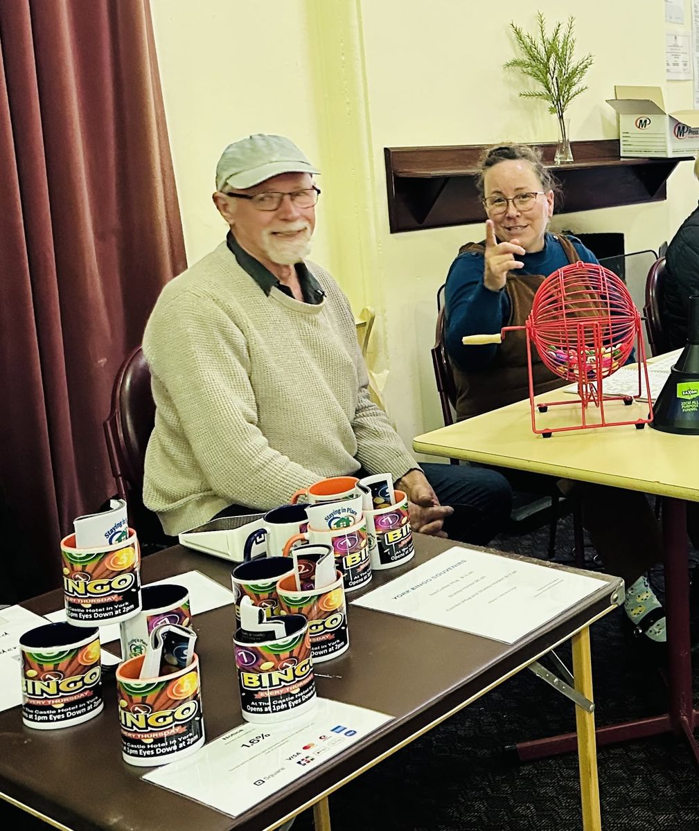 Two volunteers at the souvenir table with bingo mugs