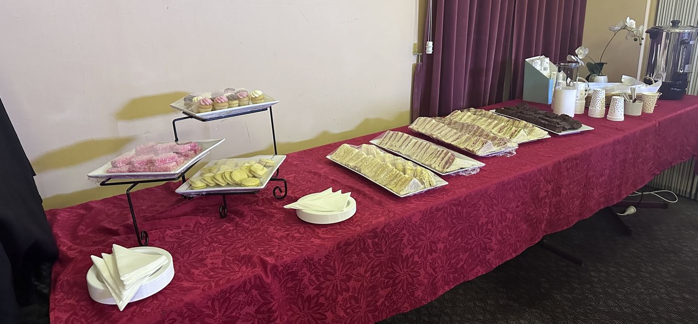 A supper table with sandwiches, slices, biscuits and cupcakes