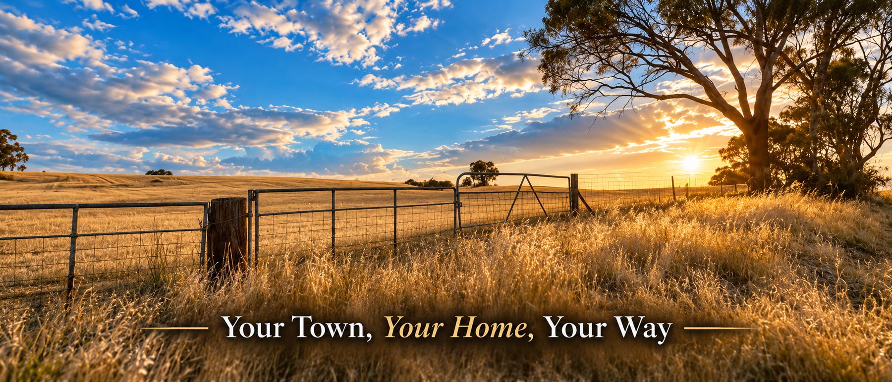 A golden paddock with farm gates and gum trees at sunset, with the words Your Town, Your Home, Your Way